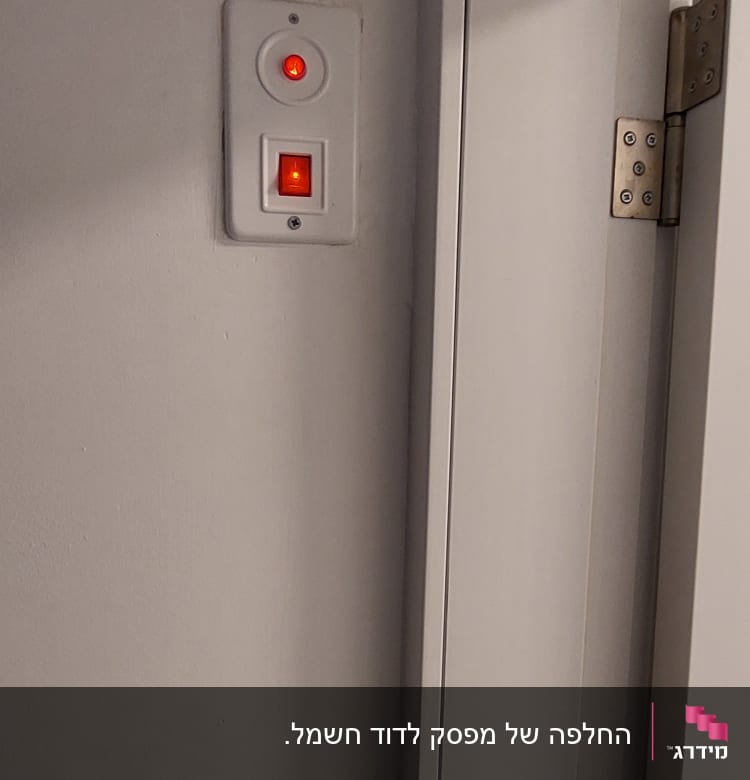 מתג חשמלי עם נורית חיווי אדומה על קיר